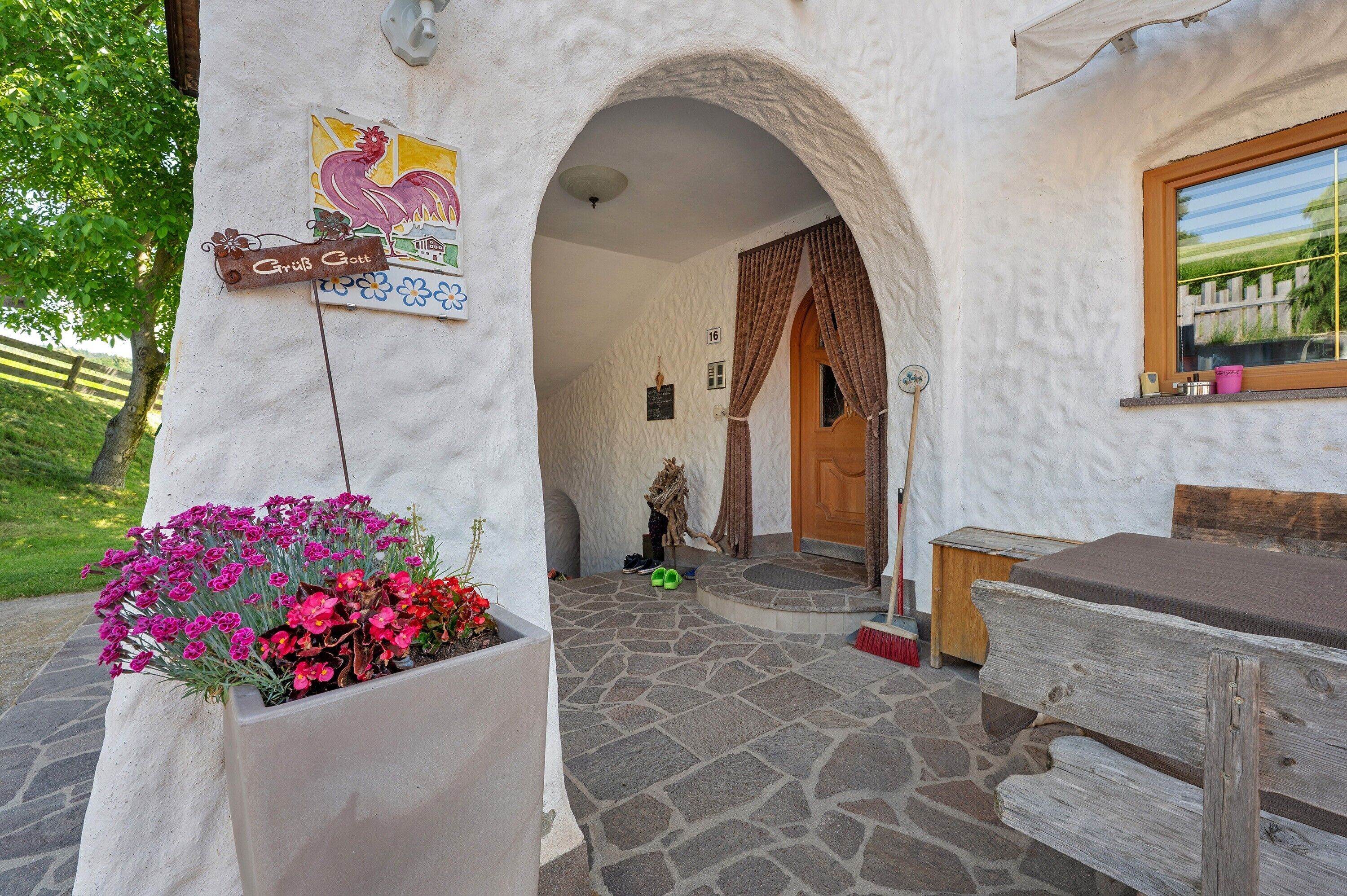 A rustic building with a stone entrance, a wooden bench, and a flower planter.