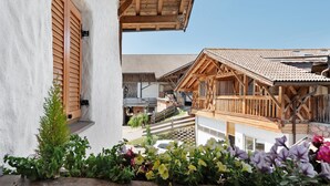 Ein traditionelles Chalet mit Holzbalkon, Steinmauer und Blick auf die Umgebung.