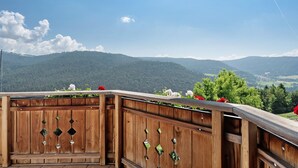 A wooden balcony with a view of green hills and a clear sky. - Apartment 'Kornblume' with Mountain View, Shared Garden and Wi-Fi (Meltina)