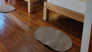 Una habitación con dos camas de madera, un banco de madera y un tapete tejido en el suelo.