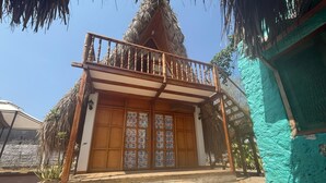 Una casa de madera tradicional con balcón, techo de paja y entrada con tejas.