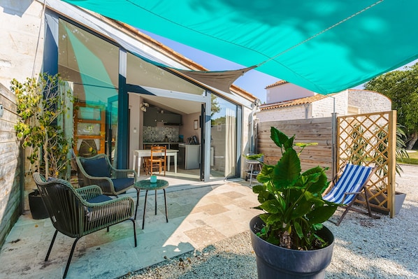 An outdoor patio area with wicker furniture, a potted plant, and a striped beach chair.