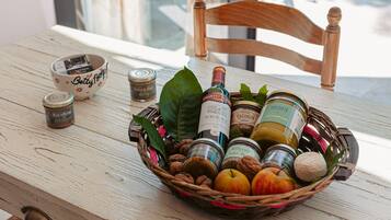 A wicker basket filled with various food items and bottles on a wooden table.