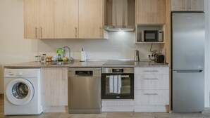 Une cuisine moderne dotée de meubles en bois, d’un lave-vaisselle, d’un four, d’un four à micro-ondes et d’un réfrigérateur.