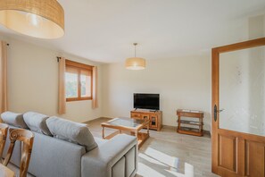 Ein Wohnzimmer mit einer Couch, einem Fernseher, einem Holzschrank und einem Glastisch.