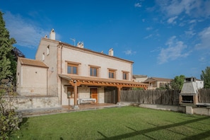 Ein zweigeschossiges Haus mit Terrasse, Grillplatz und umzäunter Garten.