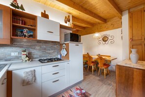 A kitchen with white cabinets, a microwave, and a stove. There is a dining area with a table and chairs.