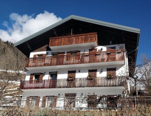 A multi-story building with wooden balconies, white walls, and a sloped roof.