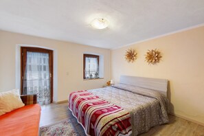 A bedroom with a bed, two windows, a ceiling light, and wall decorations. - Apartment 'La Casa Dei Cervi' with Mountain View, Balcony and Wi-Fi (Vodo Cadore)