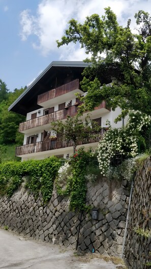 A multi-story building with balconies, surrounded by greenery and a stone wall. - Apartment 'La Casa Dei Cervi' with Mountain View, Balcony and Wi-Fi (Vodo Cadore)