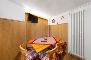 Un comedor con una mesa de madera, sillas, un televisor y un radiador.