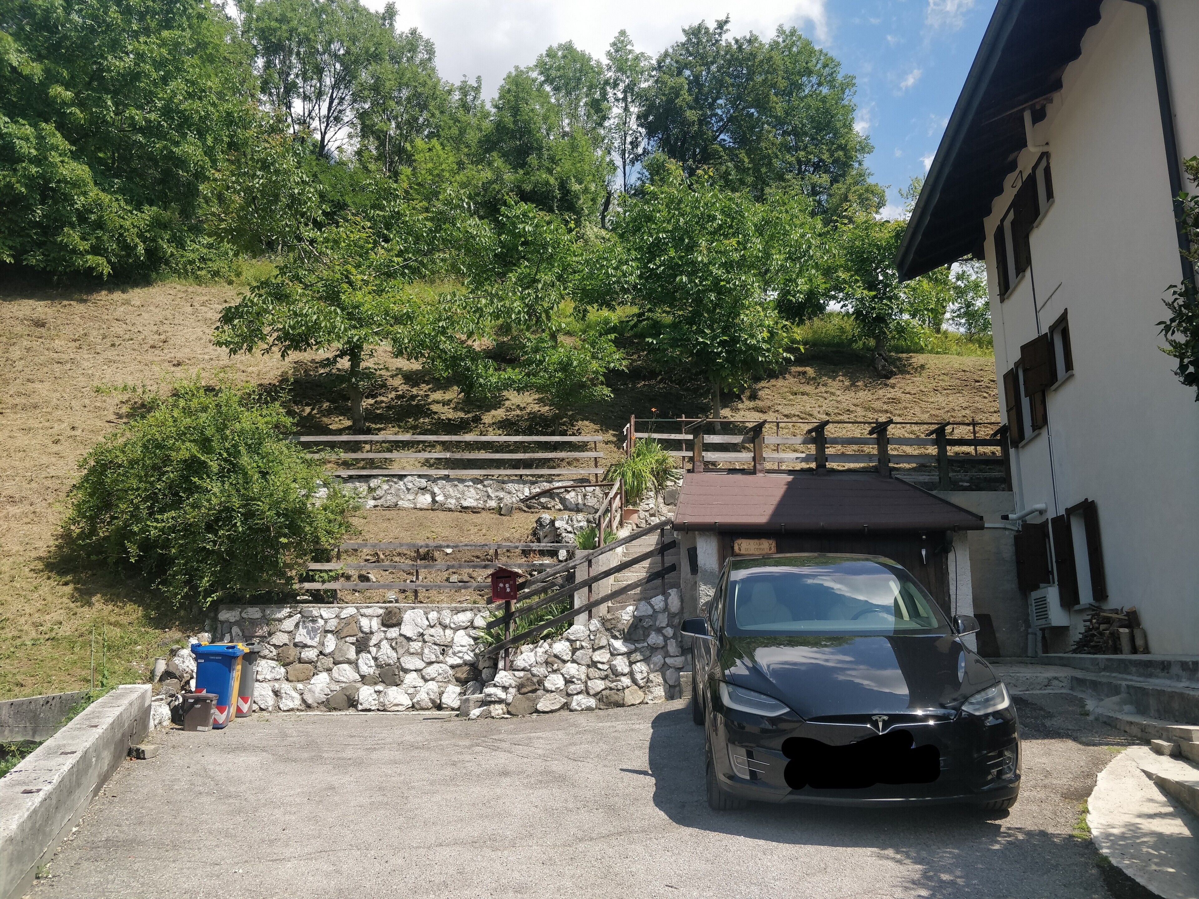 Ein Auto vor einem Gebäude mit einer Steinmauer und einer Holztreppe, die einen Hügel hinaufführt.