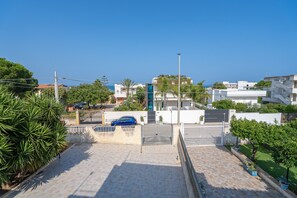A residential area with a paved driveway, a gated entrance, and modern buildings in the background. - Apartment 'Donna Di Denari' with Sea View, Wi-Fi and Air Conditioning (Noto Marina)