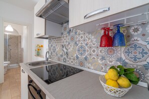 A kitchen with a sink, patterned backsplash, and a basket of lemons.