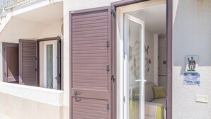 A hotel room with a sliding door, a bed, a sofa, and a wall-mounted artwork. - Apartment 'Almàsalo Re Di Coppe' with Private Terrace, Wi-Fi and Air Conditioning (Noto Marina)