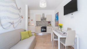 A modern kitchen with a tiled backsplash, a dining table with chairs, and a flat-screen TV mounted on the wall. - Apartment 'Almàsalo Re Di Coppe' with Private Terrace, Wi-Fi and Air Conditioning (Noto Marina)