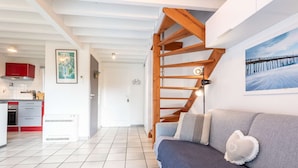 Eine moderne Küche mit roten Schränken, einem weißen Kühlschrank und einem Essbereich mit einer Holztreppe.