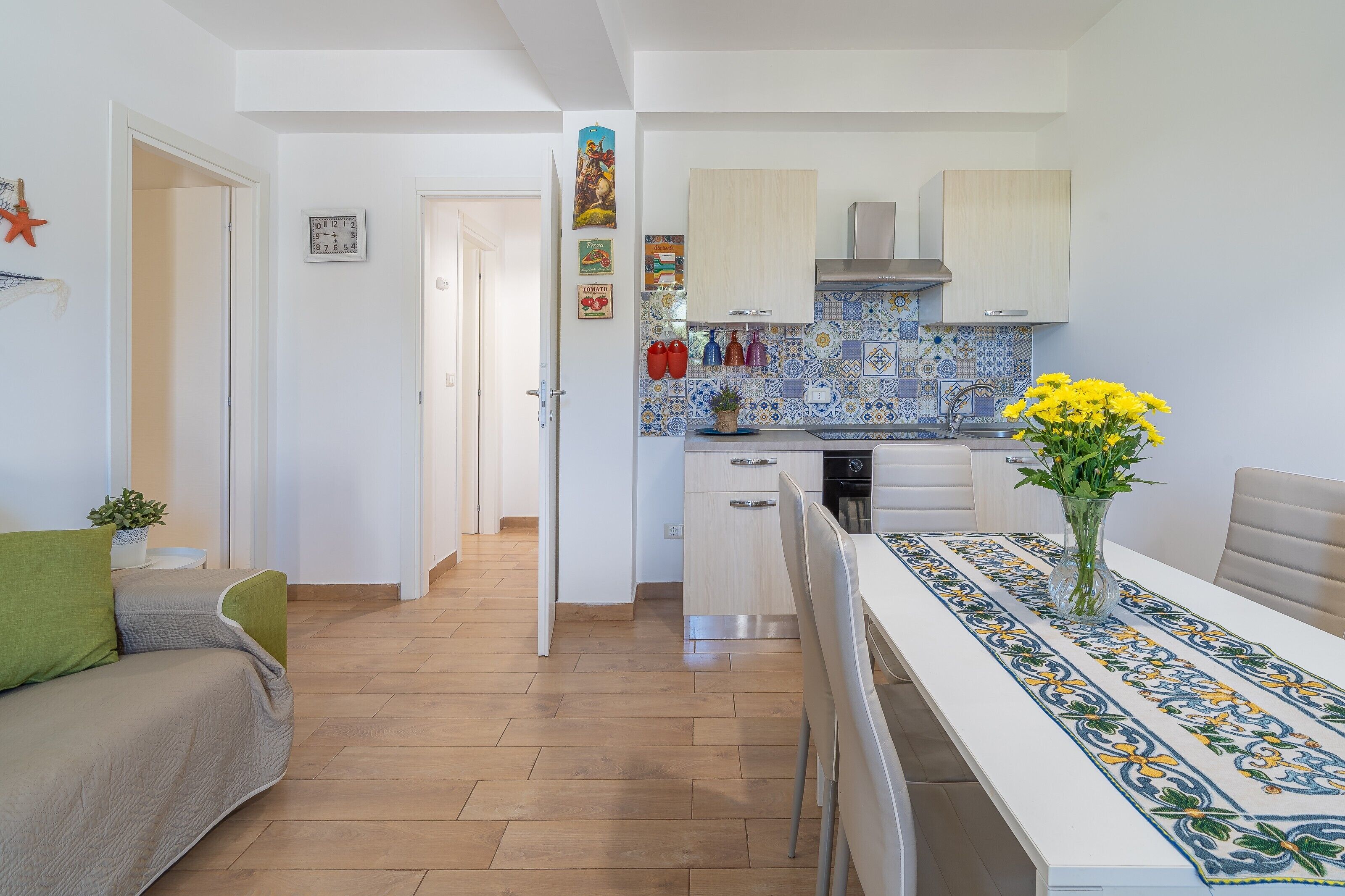 A modern kitchen with white cabinets, a tiled backsplash, and a dining area with a table set for two.