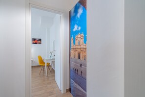 A room with a dining area, a painting of a building, and a wooden floor.