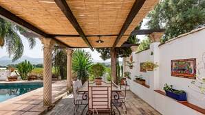 Un patio cubierto con piscina, mobiliario exterior y plantas en macetas.