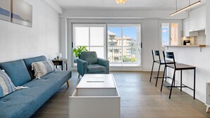 Een moderne woonkamer met een bank, fauteuil, salontafel en barstoelen.