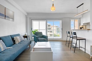 A modern living room with a sofa, armchair, coffee table, and bar stools.