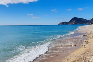 A beach with clear blue water, a sandy shore, and a mountain in the background. - Altea Cap Negret Apartment with Beach Access (Altea)