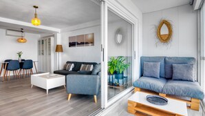 Een moderne woonkamer met een bank, een salontafel en een eethoek met stoelen.