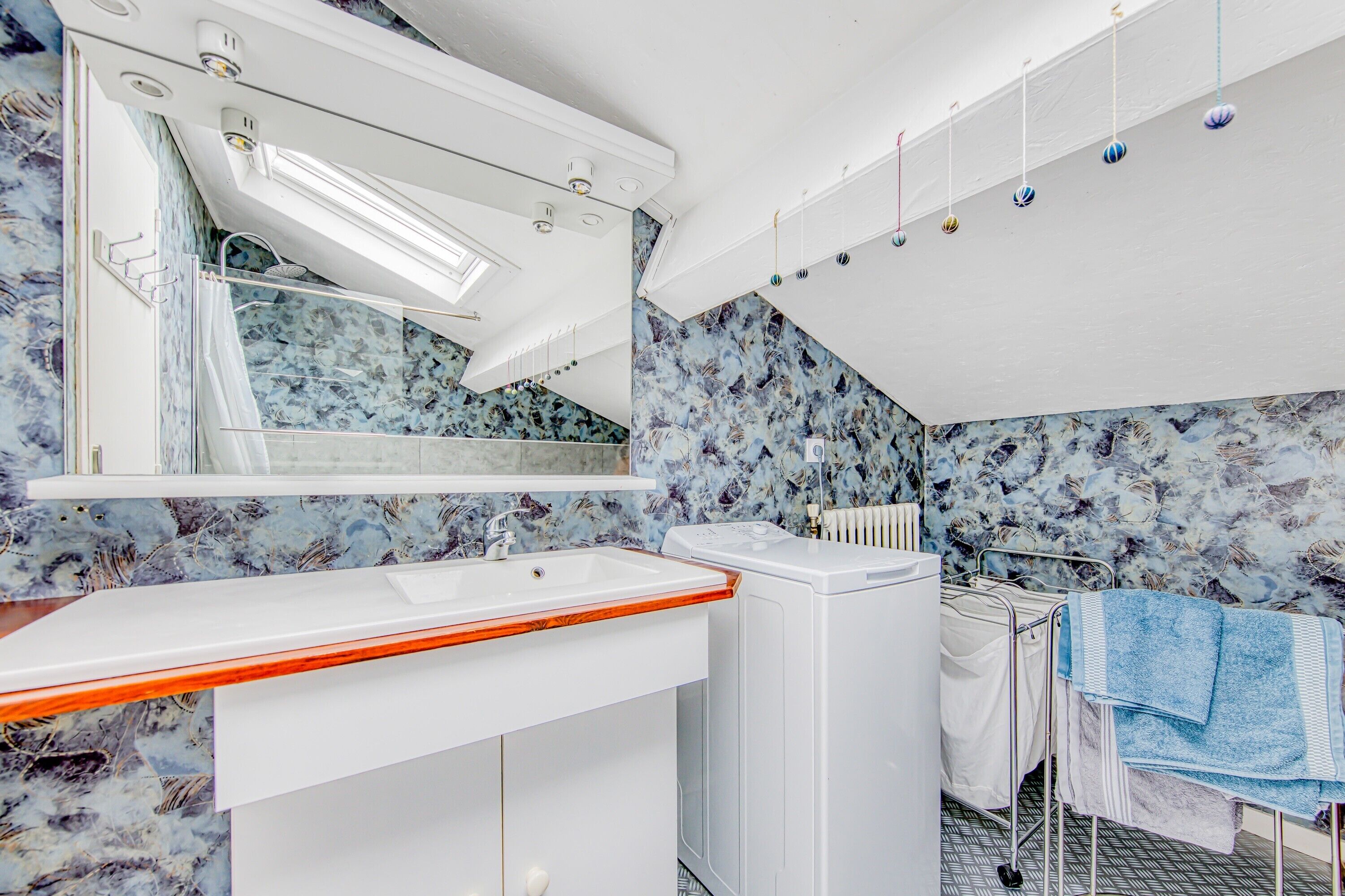 A bathroom with a white sink, a mirror, a towel rack, and a shower area.