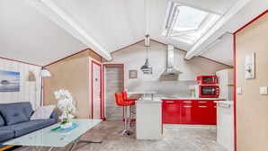 A compact living space with a kitchenette, a dining area with a glass table, and a sofa. - Le Grand T2 – Stylish Apartment with Shared Pool in Andernos-les-Bains (Andernos-les-Bains)