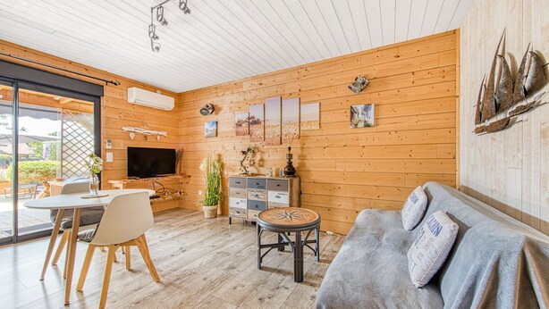 A wooden interior with a dining area, sofa, and artwork on the walls. - La Gascogne in Andernos-les-Bains – Stylish Apartment for 2, Near Nature & Coast (Andernos-les-Bains)