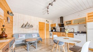 A cozy cabin interior with a wooden floor, a sofa, a dining table, and a kitchen area. - La Gascogne in Andernos-les-Bains – Stylish Apartment for 2, Near Nature & Coast (Andernos-les-Bains)