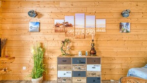 A wooden cabin interior with a wooden cabinet, a potted plant, and wall-mounted artwork. - La Gascogne in Andernos-les-Bains – Stylish Apartment for 2, Near Nature & Coast (Andernos-les-Bains)