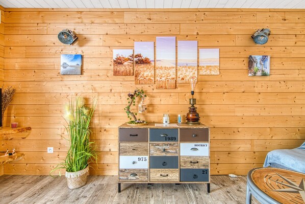 Ein Holzh ütten-Innenraum mit Holzschrank, Topfpflanze und Wandbildern.