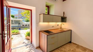 Une cuisine compacte dotée d’une cuisinière intégrée, d’un évier et d’un plan de travail en bois.