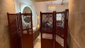Une salle de bain moderne avec un séparateur en bois, un lavabo et un lustre.