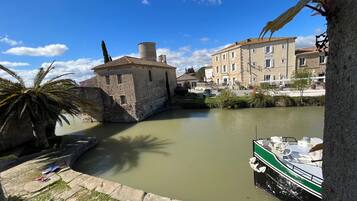 Un edificio storico con facciata in pietra, una palma e una barca ormeggiata sull'acqua.