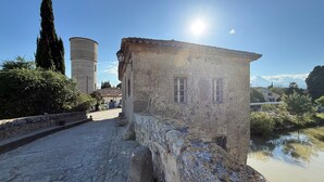 Un bâtiment en pierre doté de deux fenêtres, un mur en pierre et un chemin pavé.