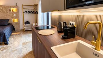 Une cuisine moderne équipée d’un évier encastré, d’une machine à café et d’une bouilloire posées sur le plan de travail.