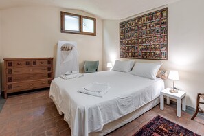 Una camera da letto con un letto grande, una cassettiera, un tavolino, una lampada e un'opera d'arte a parete.