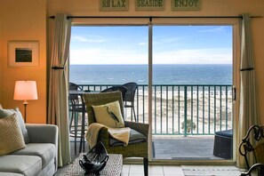 Ein Zimmer mit Blick auf den Strand, ein Korbsessel, ein Tisch mit einer schwarzen Schüssel und eine Lampe.
