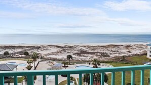 A beachfront property with a pool, a beach, and a pier.