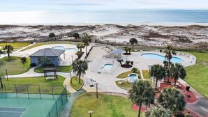 A resort with multiple swimming pools, a tennis court, and a beach view.