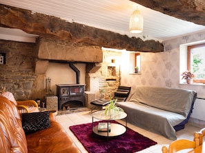 A rustic room with a stone fireplace, a sofa, a coffee table, and a hanging light fixture.