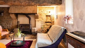 A cozy living room with a stone fireplace, a piano, and a comfortable seating area. - Holiday Home 'De L'alliance' with Private Terrace and Private Garden (Lannion)