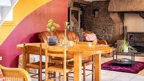 A cozy room with a wooden dining table, chairs, a stone fireplace, and a vibrant wall. - Holiday Home 'De L'alliance' with Private Terrace and Private Garden (Lannion)