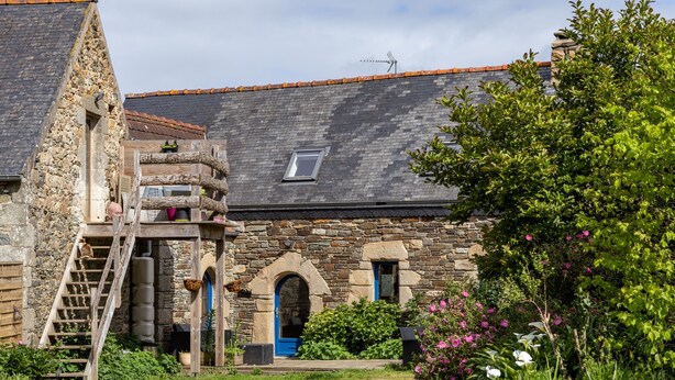 A stone building with a wooden staircase, a small balcony, and a garden with flowers. - Holiday Home 'De L'alliance' with Private Terrace and Private Garden (Lannion)