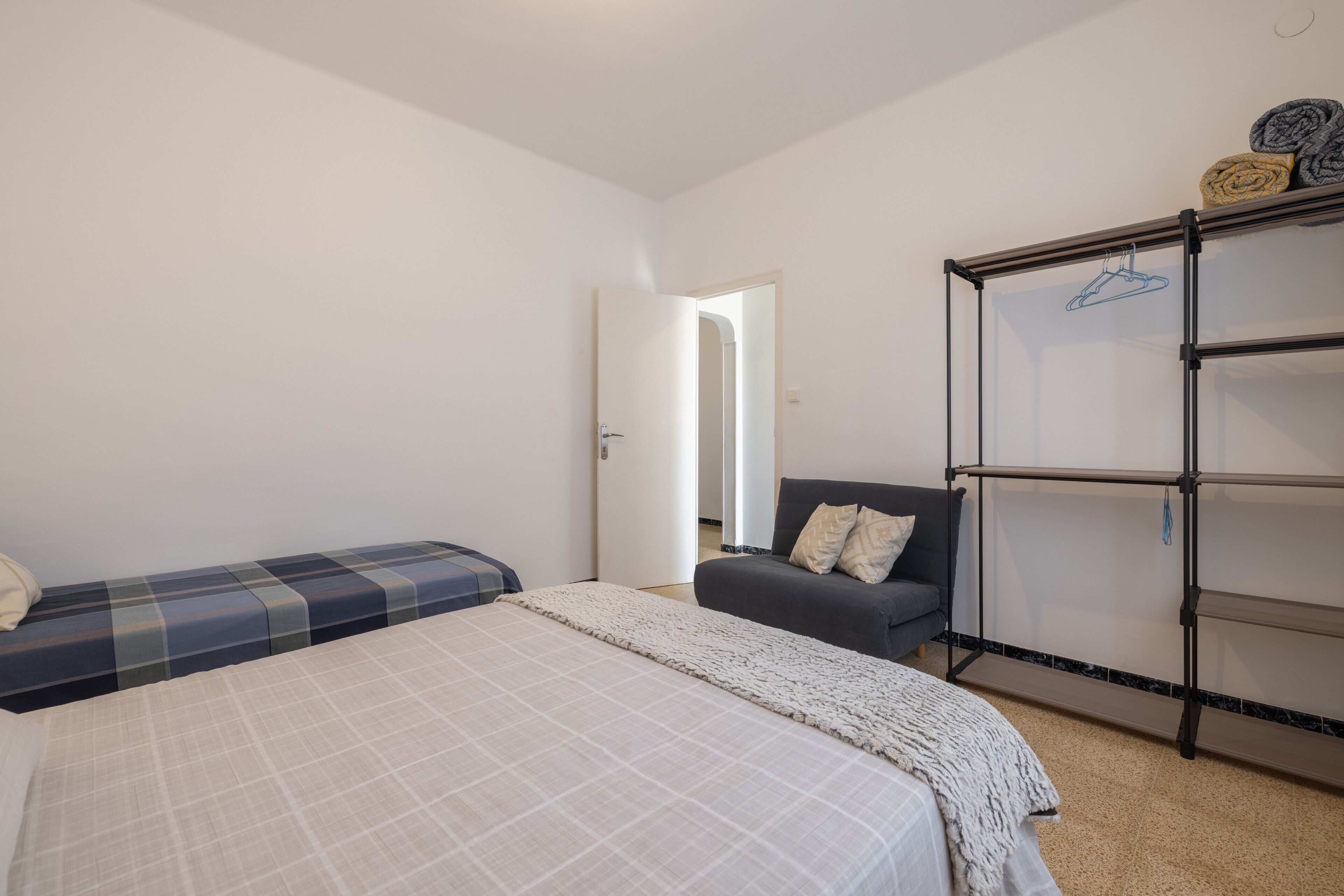 Un dormitorio con cama, sofá, armario y puerta que da a otra habitación.