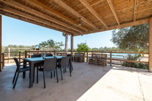 Une terrasse extérieure dotée d’un plafond en bois, d’une table avec des chaises et d’une vue sur une piscine.