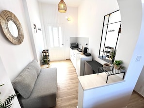Ein kompakter Wohnbereich mit Küchenzeile, einer Couch, einem Essbereich und einer Treppe.